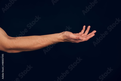 Man hand isolated on dark blue background. Holding something from below. Asking for help gesture