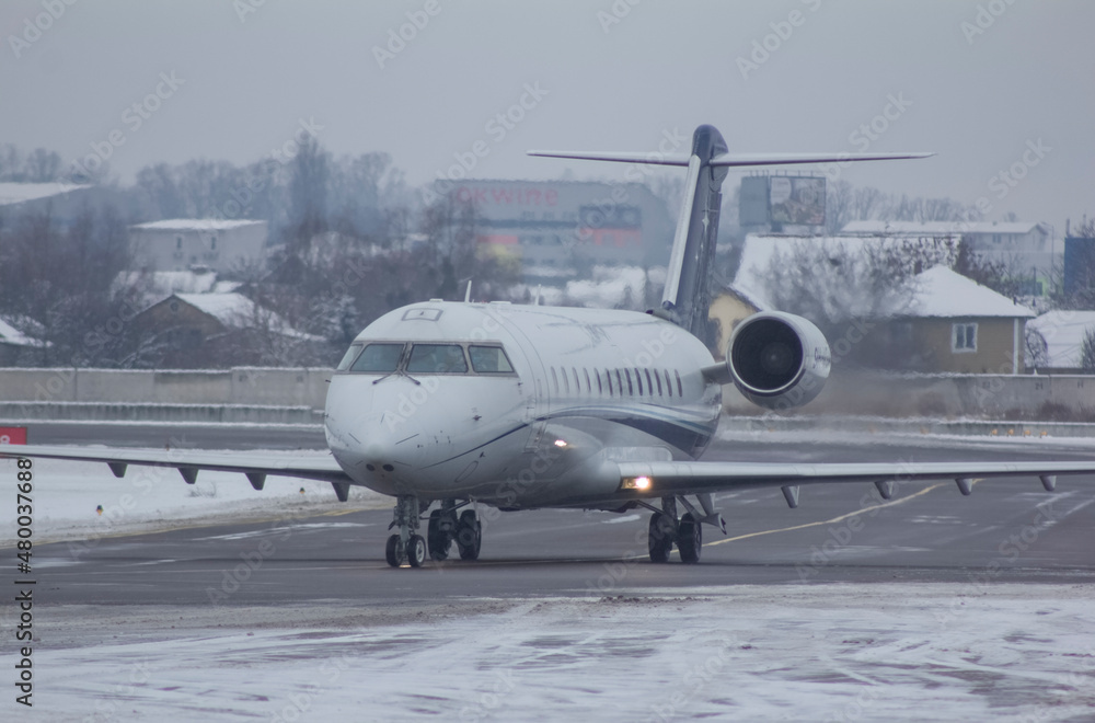 A private twin-engine jet aircraft is parked with its landing lights on. A private twin-engine jet aircraft is parked with its landing lights on.