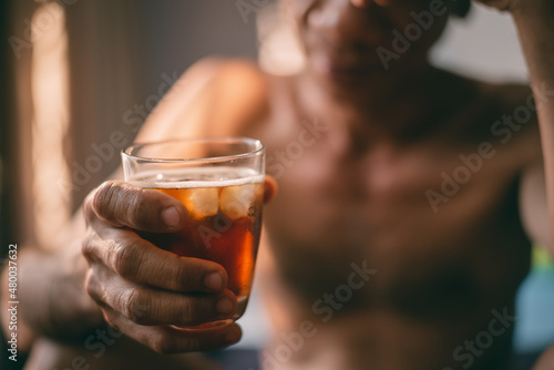 Liquor glass in the hands of a middle-aged man, concept of poor man alcohol addiction and depression because of life problems, Strain during the economy has stalled due to covid pandemic, Cinema tone.
