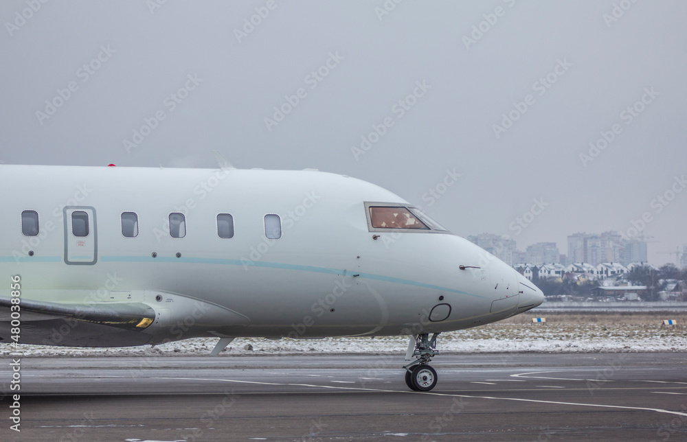 A twin-engine jet plane stands at the airport in the parking lot at winter 
