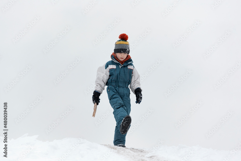 Cute boy in warm hat walking in winter Park. Child walks in the snow. Walk outside on cold winter day. Cute boy in warm hat walking in winter Park. Child walks in the snow. Walk outside on cold winter day.