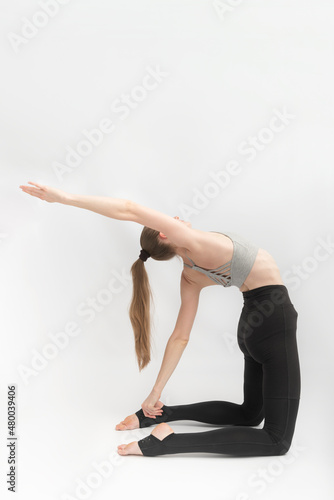 Girl practices yoga at Camel Pose. Ustrasana. Young woman yoga instructor performs asana. Vertical frame