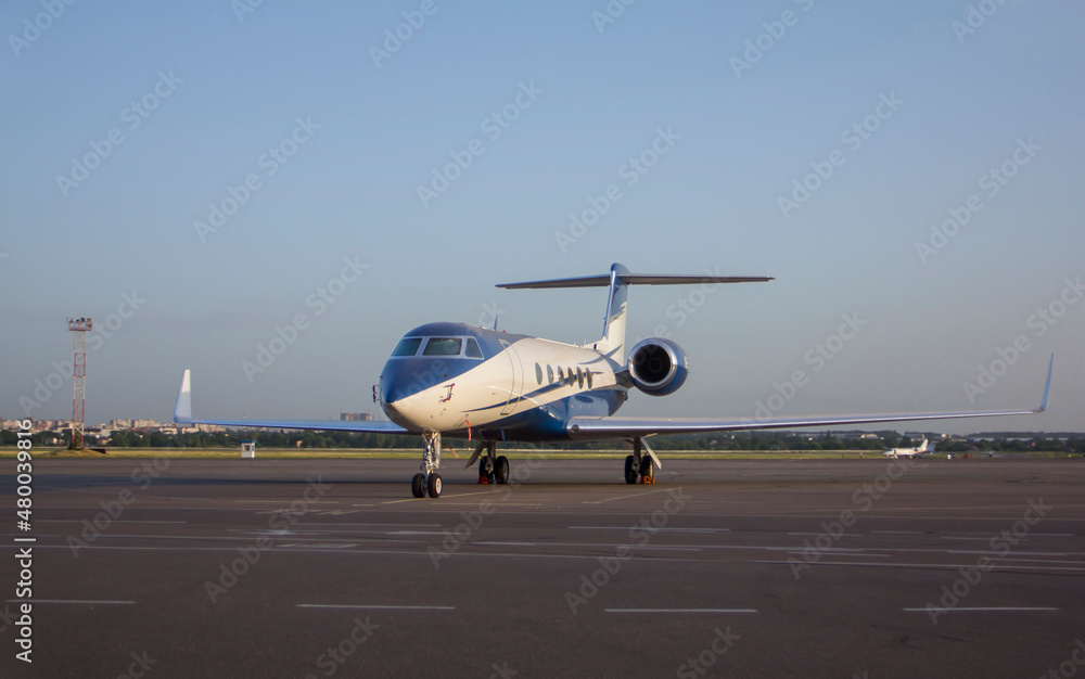 A twin-engine business jet plane stands at the airport in the parking lot at summer A twin-engine business jet plane stands at the airport in the parking lot at summer