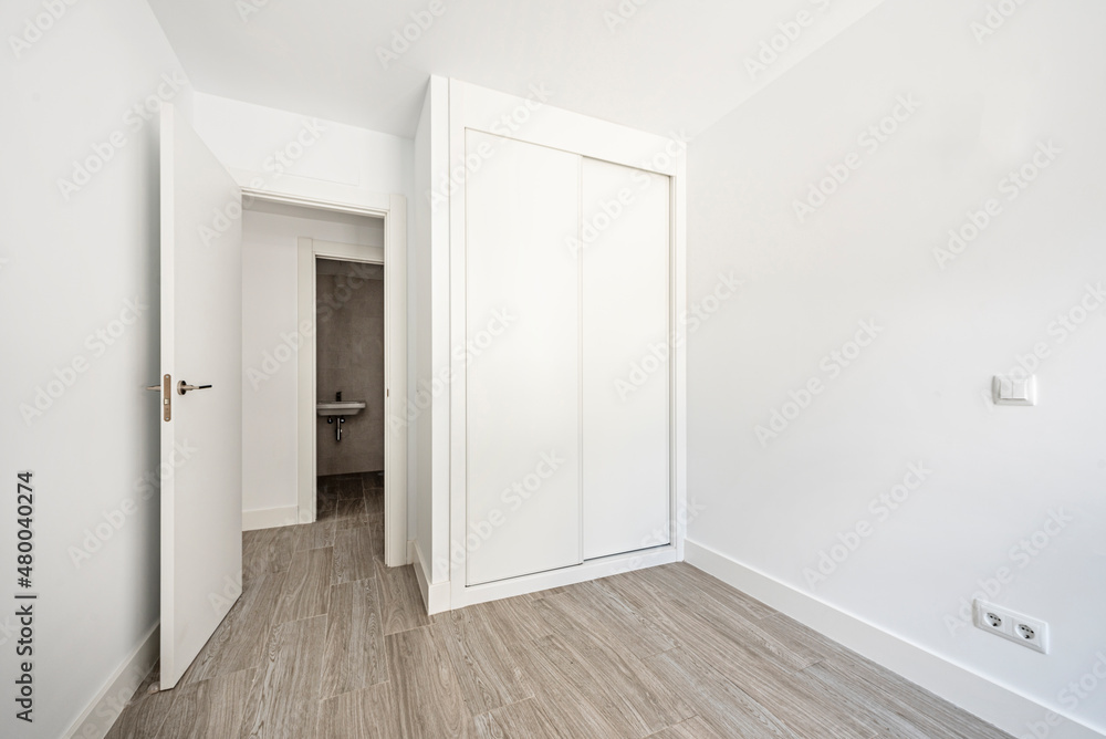 Room with built-in wardrobe with sliding doors and white wood carpentry with porcelain stoneware floors Room with built-in wardrobe with sliding doors and white wood carpentry with porcelain stoneware floors