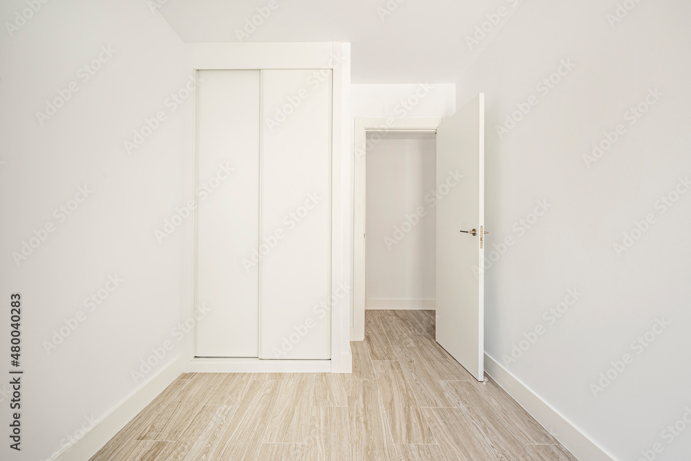 Room with built-in wardrobe with sliding doors and white wood carpentry with porcelain stoneware floors Room with built-in wardrobe with sliding doors and white wood carpentry with porcelain stoneware floors