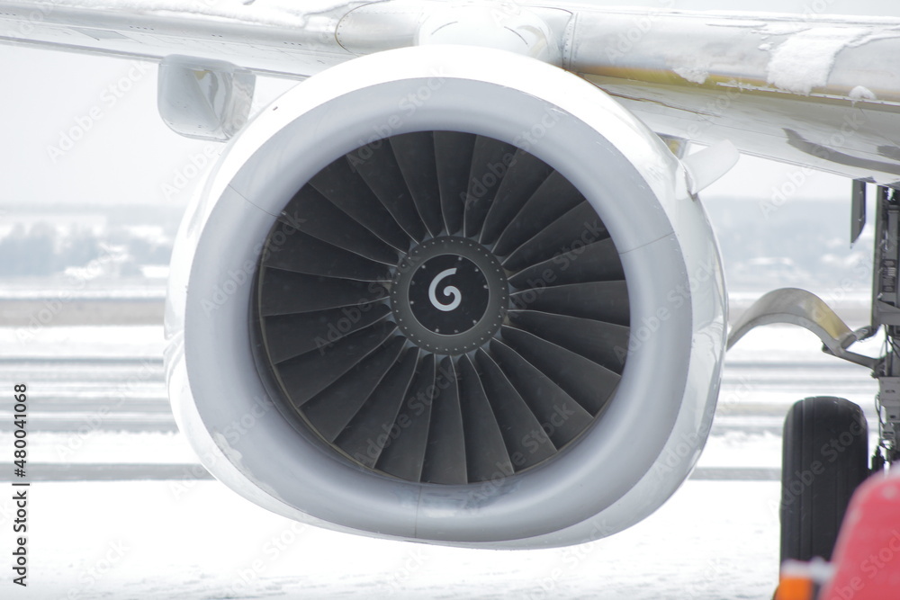 Aircraft jet engine of a liner, turbine blades on the background of the airport in winter Aircraft jet engine of a liner, turbine blades on the background of the airport in winter