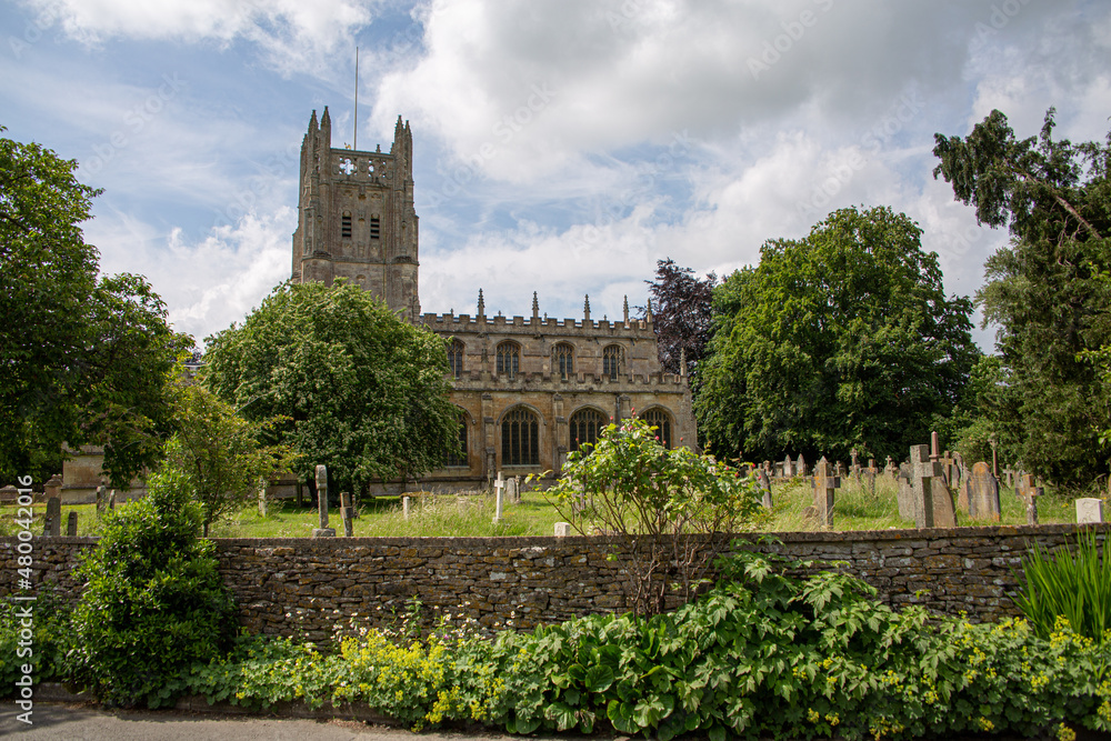 St Mary's Church behind stone wall during summer with blue sky and clouds in the background