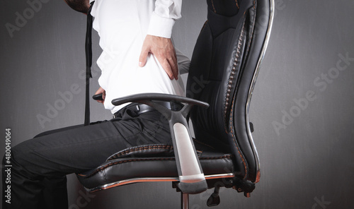 Businessman with back pain sitting in office chair. © andranik123