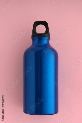 Top view of blue aluminum sport water bottle on pink background