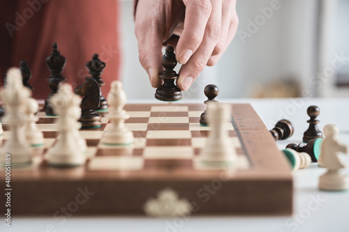 Valokuvatapetti Chess game, hand moves black bishop across the chessboard