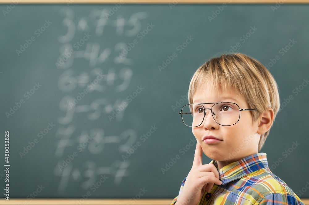 Student child writes with chalk on a blackboard solution of an example in mathematics. Student child writes with chalk on a blackboard solution of an example in mathematics.