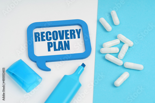 On the white and blue surface are a marker, tablets and a plate inside which the inscription - RECOVERY PLAN