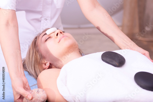 Young women having heated stones massage in a beauty clinic