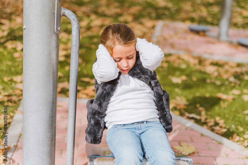 Caucasian little girl doing push-ups on a park exercise machine. Bio-healthy park concept.
