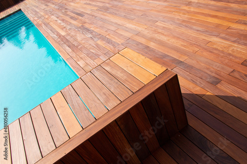 Diagonal lines of wood tiles, ipe exotic hardwood around the blue water swimming pool