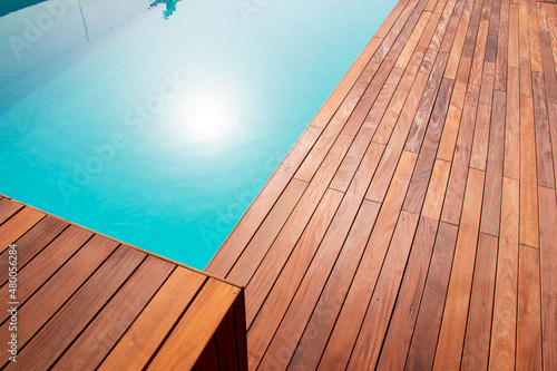 Texture with tiled wooden decorative planking, hardwood ipe pool deck shining sun reflecting on the water