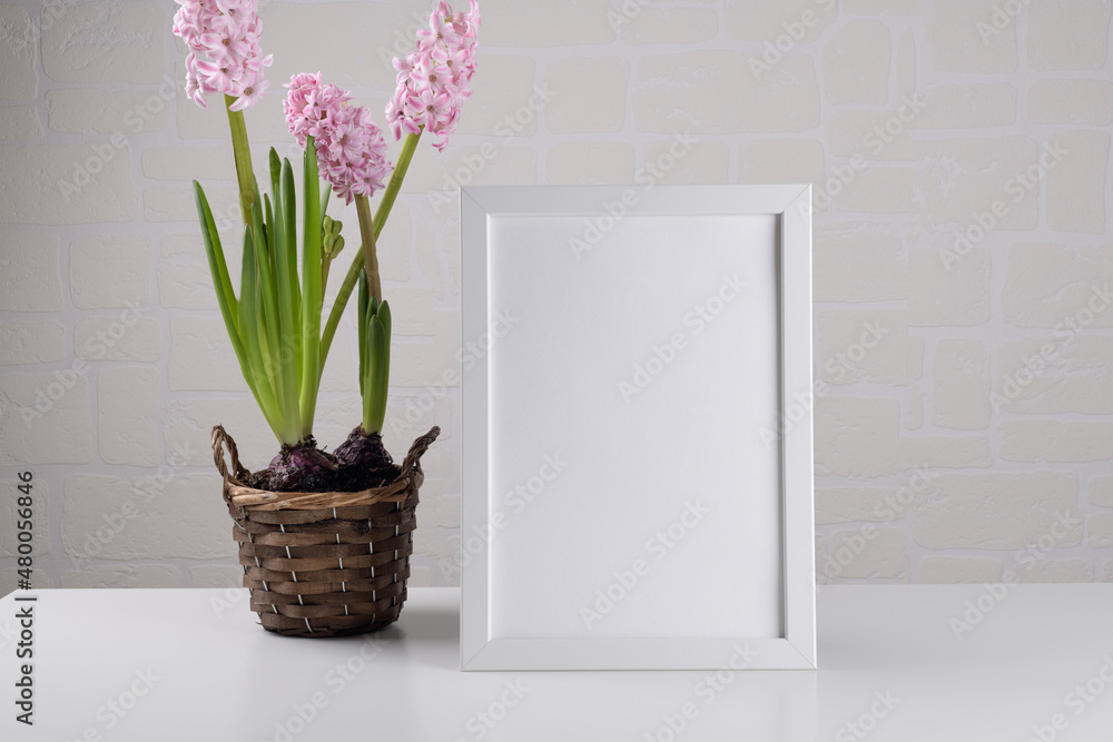 Portrait a4 white wooden frame mockup with pink hyacinth flower on the table on white wall of room. Poster mockup. Clean, modern, minimal frame. Empty frame Indoor interior, show text or product Portrait a4 white wooden frame mockup with pink hyacinth flower on the table on white wall of room. Poster mockup. Clean, modern, minimal frame. Empty frame Indoor interior, show text or product