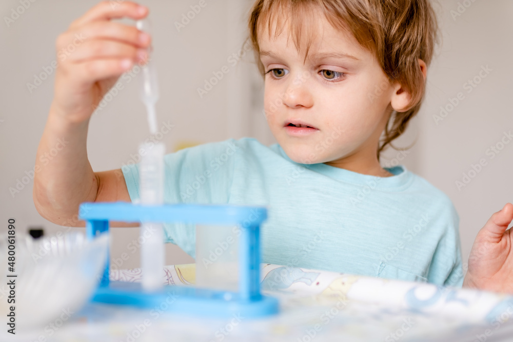 Happy boy in blue T-shirt conducts chemical experiments with vinegar and soda at home Happy boy in blue T-shirt conducts chemical experiments with vinegar and soda at home