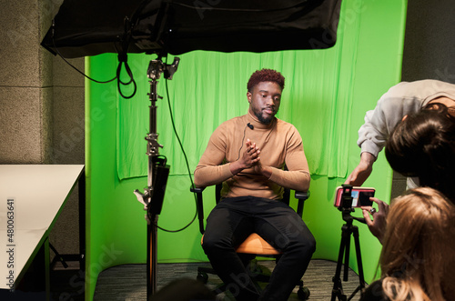 Blogger presenting report in television studio over the chroma key background