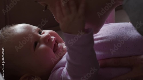 Portrait of baby and smiling mother lying on bed looking at each other, kissing stomach. Family care. Baby care. photo