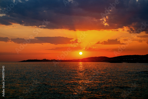 Sea sunset. Vanilla orange sky at sunset with clouds and calm sea horizon. A horizontal shot of the sky in vibrant colors. Beauty in nature.