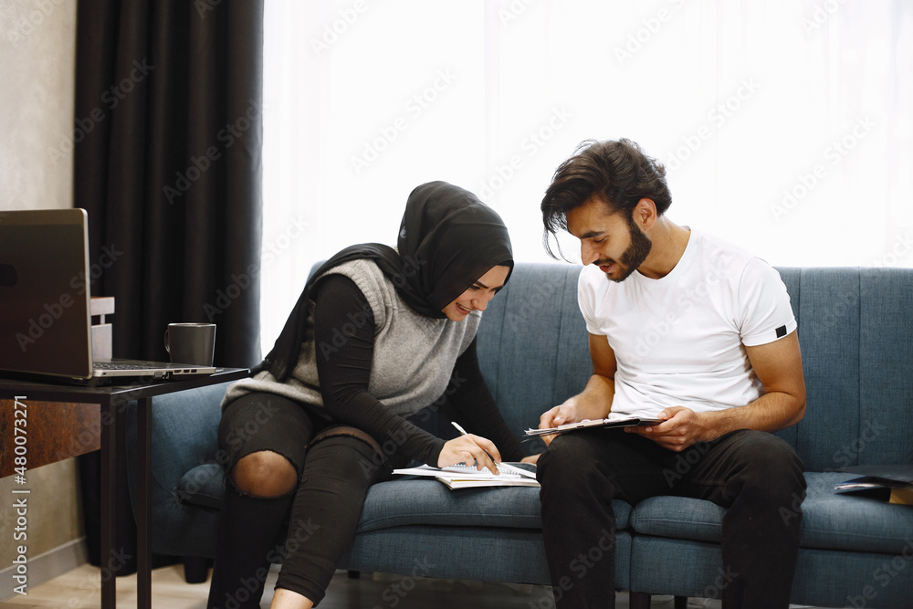 Young students, arab couple preparing for exams in apartment interior Young students, arab couple preparing for exams in apartment interior