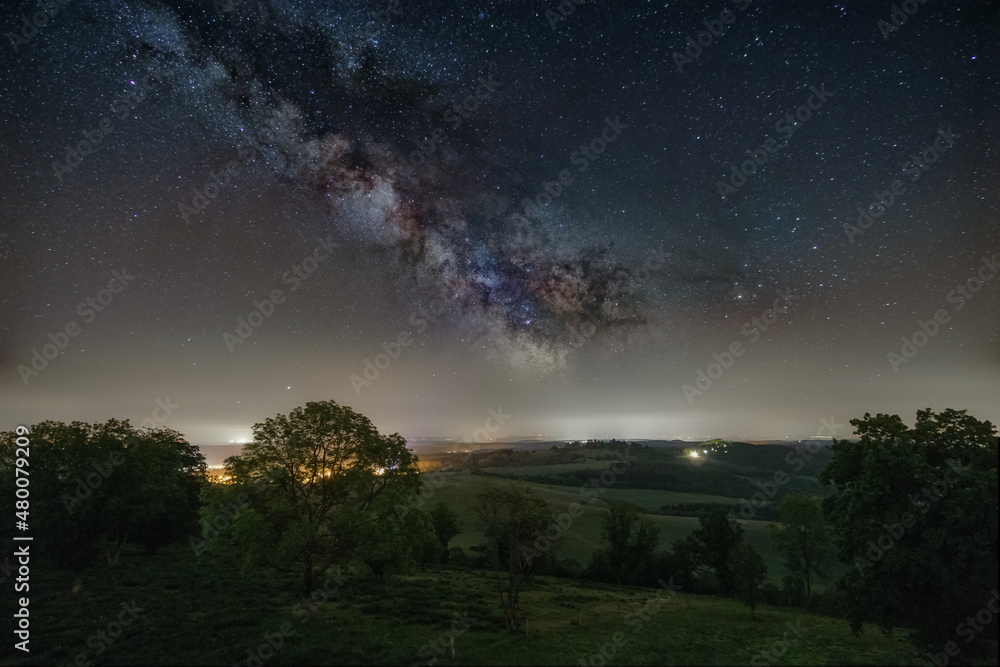 Milky Way over rural landscape with meadow full of trees