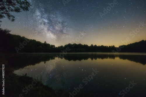 The Milky Way over volcanic lake of Weinfelder Maar in the Eifel with reflection of stars on water surface, Daun, Germany © Sebastian