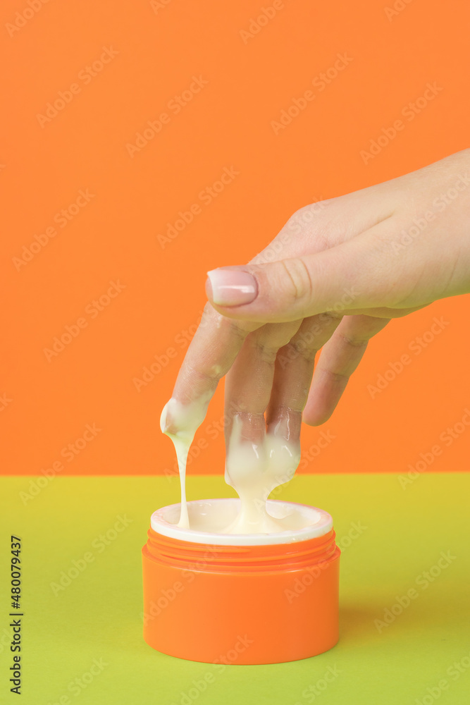 A girl taking a cosmetic cream from an orange jar. A girl taking a cosmetic cream from an orange jar.