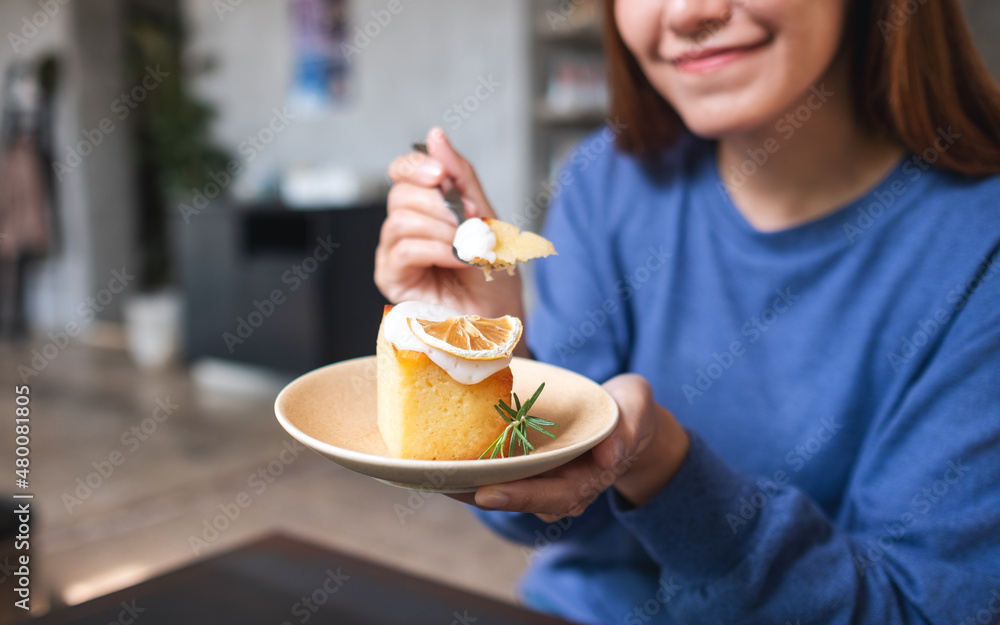Closeup of a young woman holding and eating a piece of lemon pound cake Closeup of a young woman holding and eating a piece of lemon pound cake