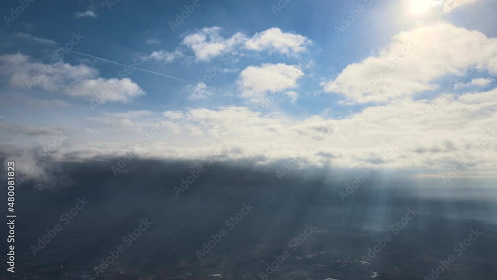 Aerial view from high altitude of distant city covered with puffy cumulus clouds flying by before rainstorm. Airplane point of view of landscape in cloudy weather Aerial view from high altitude of distant city covered with puffy cumulus clouds flying by before rainstorm. Airplane point of view of landscape in cloudy weather