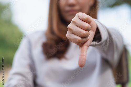 Closeup image of a woman making thumbs down hands sign photo