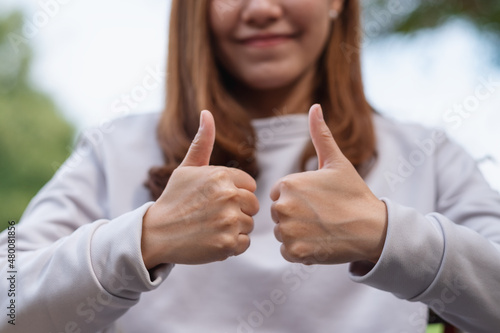 Bild auf Leinwand Closeup of a young woman making and showing thumbs up hand sign