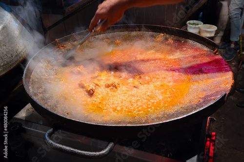 Spicy chicken curry is being prepared with heat at evening for sale as street food in Old Delhi market. The place is very famous for spicy Indian non vegetarian street foods. photo