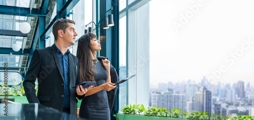 Executive businessman and his secretary is working in modern skyrise office in city downtown looking out the window with skyscraper view for business investment dreams and futuristic vision concept photo