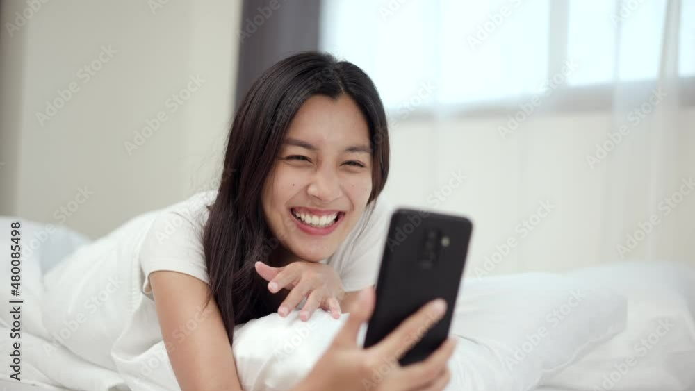 Pretty asian woman using smart phone on bed to Vdo call social media at home. Lifestyle of young beautiful female using mobile phone to network internet online before sleep. Pretty asian woman using smart phone on bed to Vdo call social media at home. Lifestyle of young beautiful female using mobile phone to network internet online before sleep.