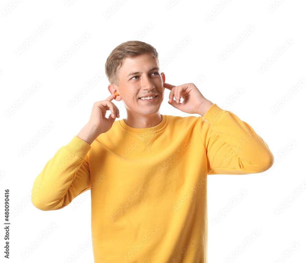 Handsome young man inserting earplugs on white background Handsome young man inserting earplugs on white background