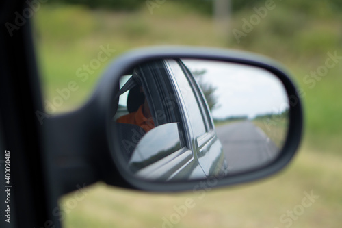 reflection in the mirror of a car where the road can be seen 