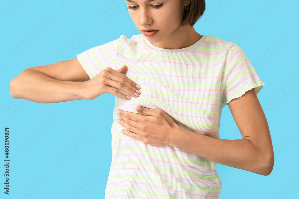 Young woman feeling discomfort in her breast on color background. Cancer awareness concept Young woman feeling discomfort in her breast on color background. Cancer awareness concept