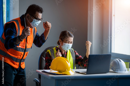 Engineer and architect protects himself from covid-19 (coronavirus) with a protective mask working with laptop computer in the construction site.