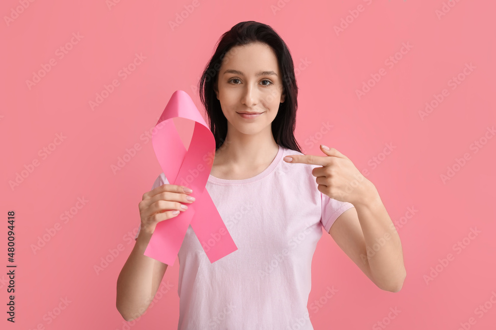 Young woman with ribbon on pink background. Breast cancer awareness concept Young woman with ribbon on pink background. Breast cancer awareness concept