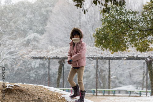 雪が降っている公園で遊んでいる可愛い子供