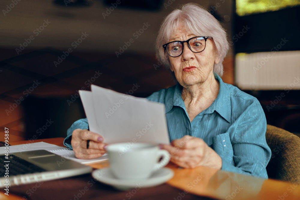 Portrait of an elderly woman sitting in a cafe with a cup of coffee and a laptop Freelancer works unaltered Portrait of an elderly woman sitting in a cafe with a cup of coffee and a laptop Freelancer works unaltered