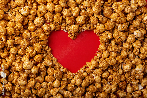 love concept image of heart shape frame made of caramel popcorn on red background
