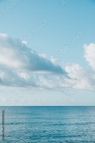 Blue calm sea in sunny weather against the background of large clouds