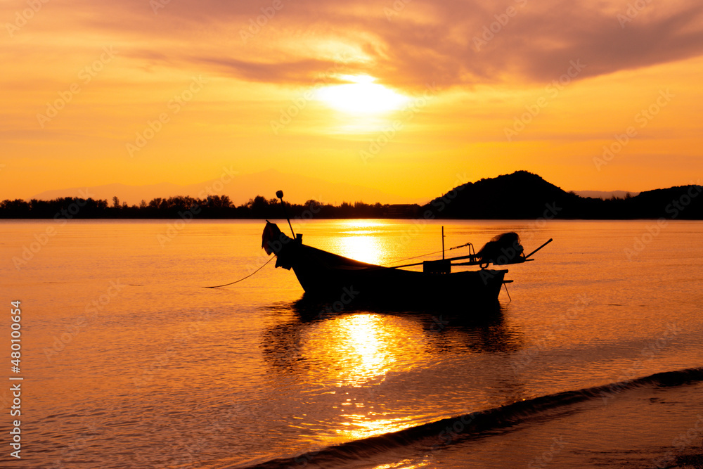 boat of fisherman on the beach with silhouette orange light before sunset and mountain background Asia Thailand