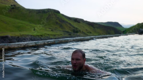 Man Swimming In Seljavallalaug Outdoor Pool In Southern Iceland. medium shot photo