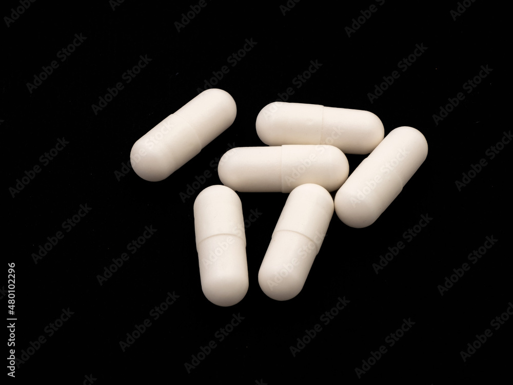 Pile of white capsules with medicine isolated on black background Pile of white capsules with medicine isolated on black background