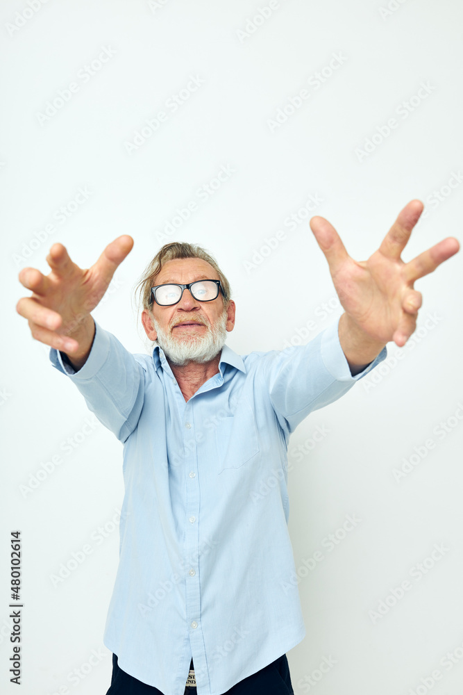 Photo of retired old man in blue shirts gestures with his hands isolated background Photo of retired old man in blue shirts gestures with his hands isolated background