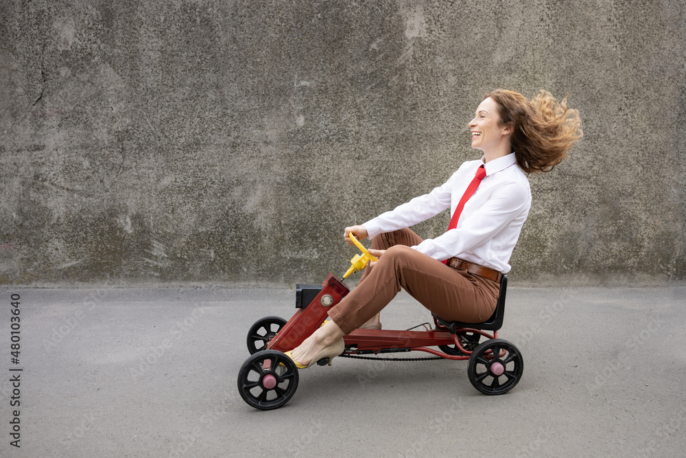 Funny businesswoman driving retro pedal car outdoor Funny businesswoman driving retro pedal car outdoor
